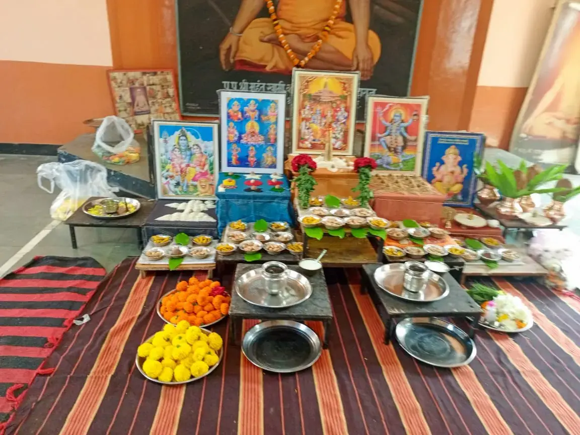 Family puja shrine with deity portraits, marigold plates and ritual vessels